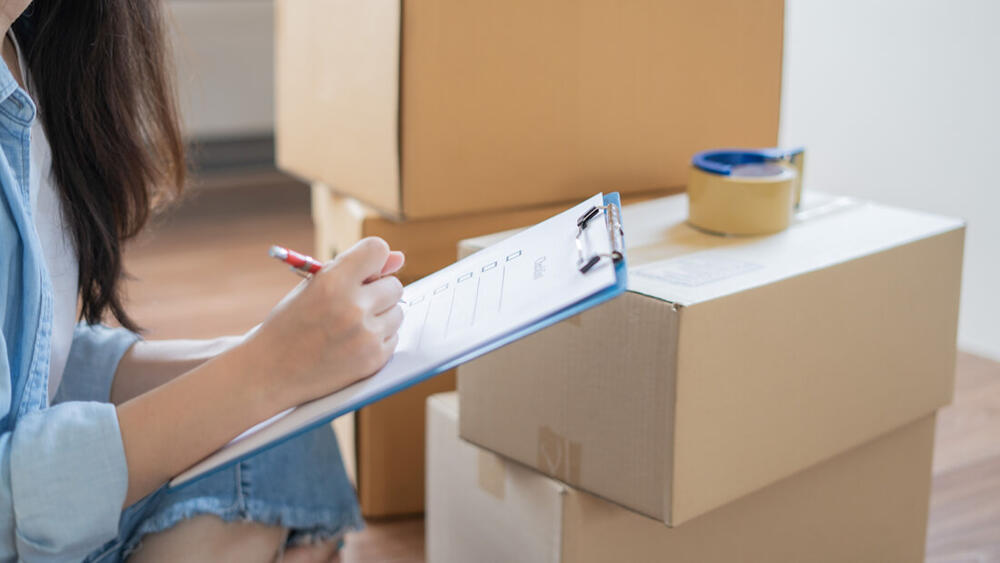 Person checking moving checklist near packed boxes