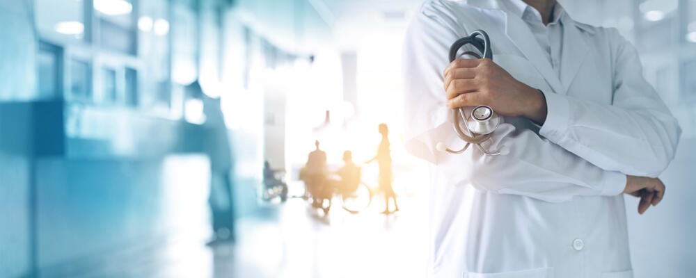 A doctor with a stethoscope standing in a hospital hallway.