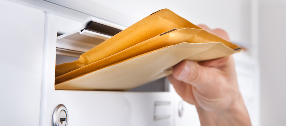 Padded envelopes being pushed through a postal slot